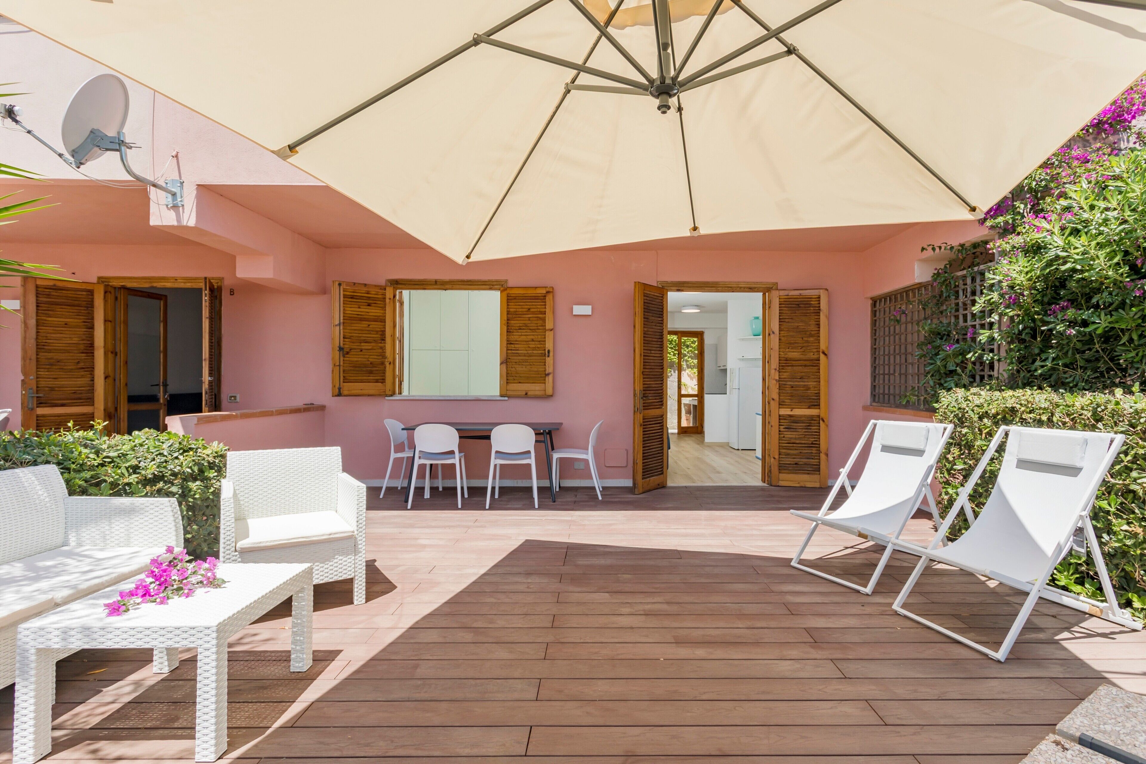 Un patio exterior con una mesa, sillas, un sofá blanco y una sombrilla grande.