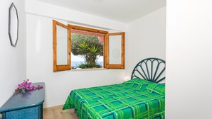 Ein Schlafzimmer mit Bett, Fenster mit Aussicht, einem Schminktisch und einem Stuhl.