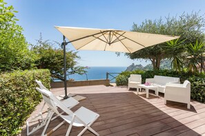 A deck with white lounge chairs, a sofa, and a table, overlooking a scenic view of the sea. - Apartment 'Paradise Residence 2' with Sea View, Wi-Fi and Air Conditioning (Sant'Alessio Village)