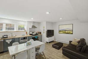 A modern kitchen with a dining area, a flat-screen TV, and a large landscape painting on the wall. - Urban oasis, Central District - Studio (Seattle)