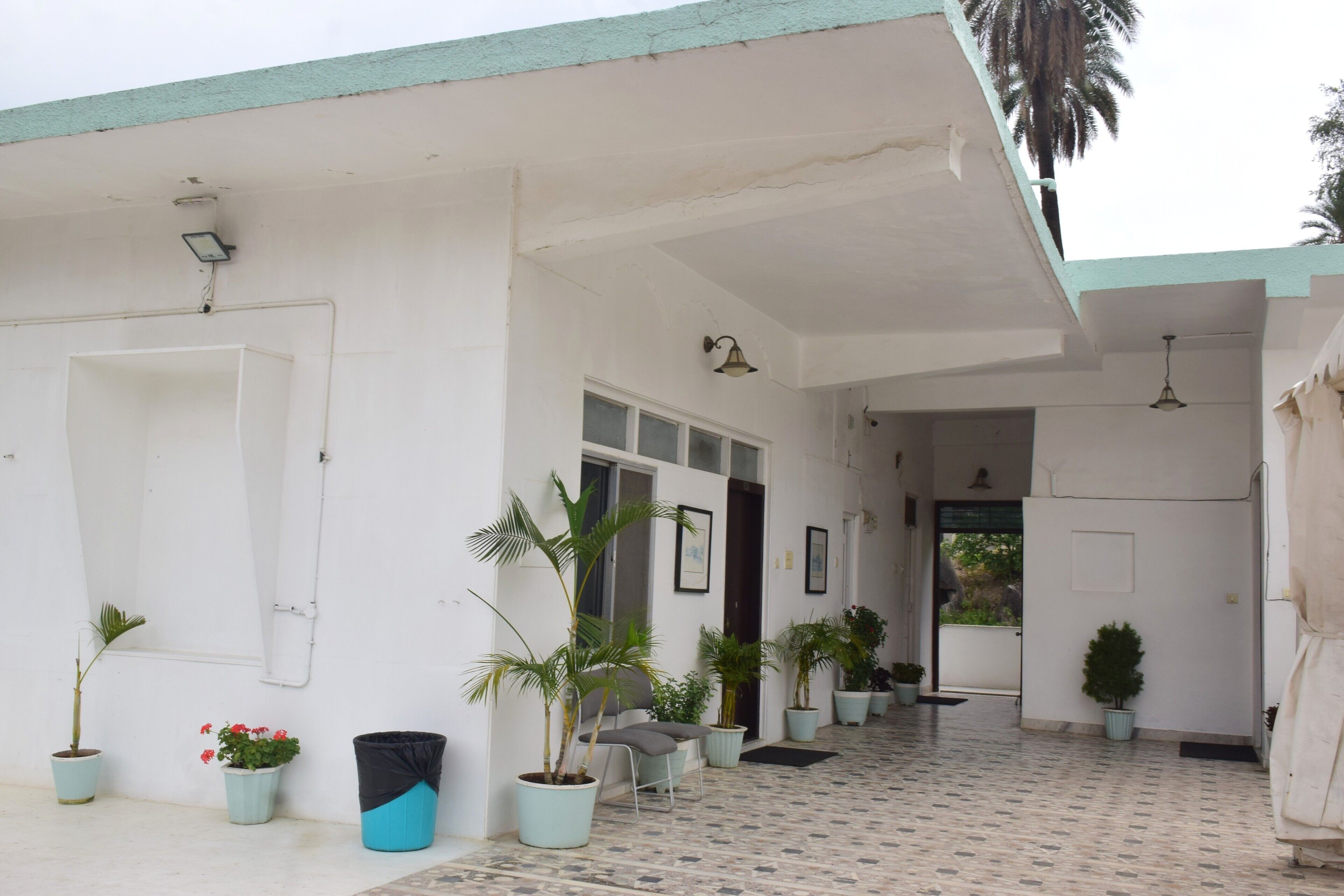 A building with a tiled floor, potted plants, and a door.