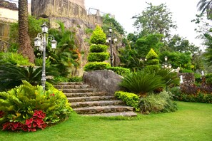 A garden with stone steps, lush greenery, and decorative lanterns. - LAKE INN (Mount Abu)