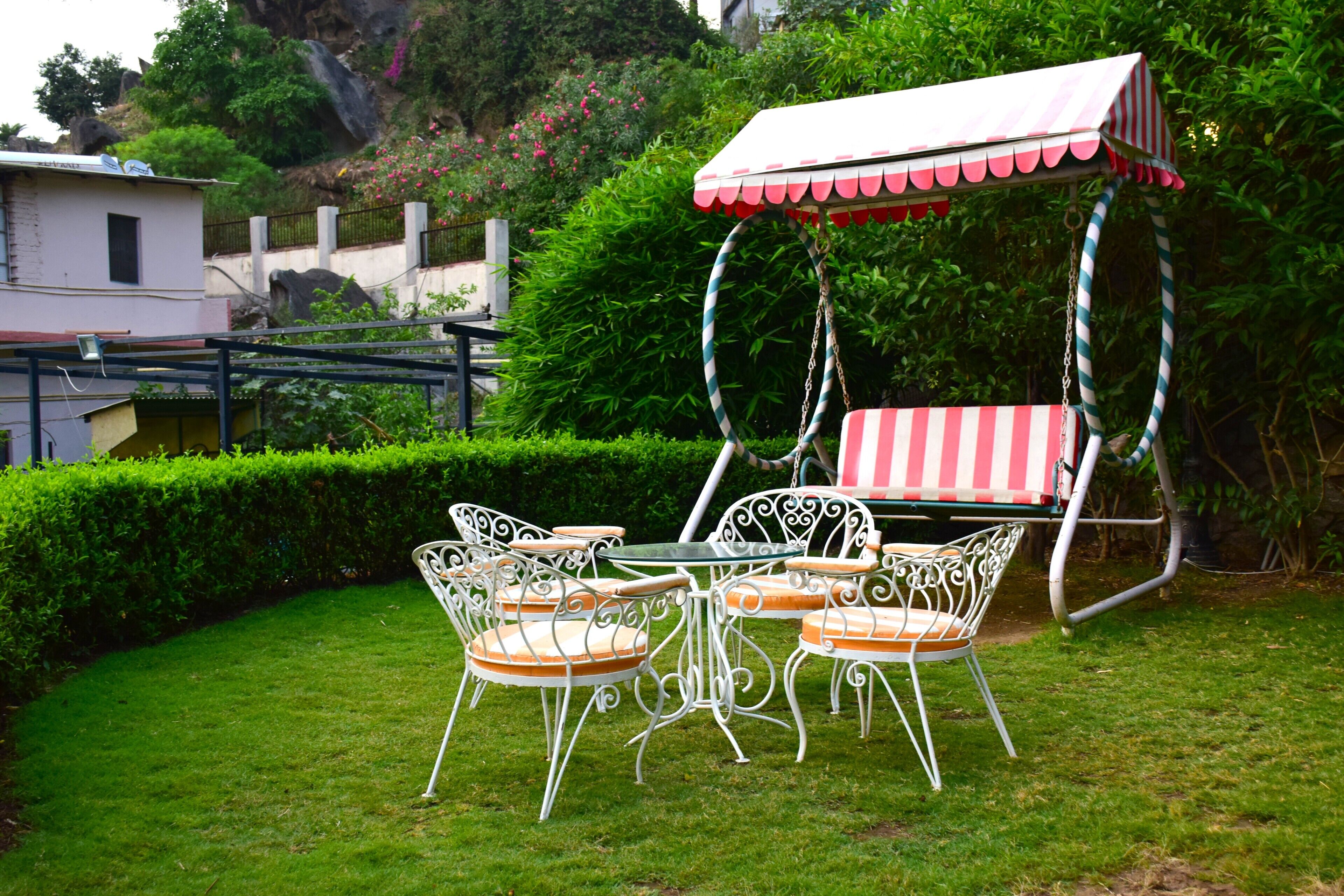 Un patio con una silla mecedora y una mesa, rodeado de follaje.