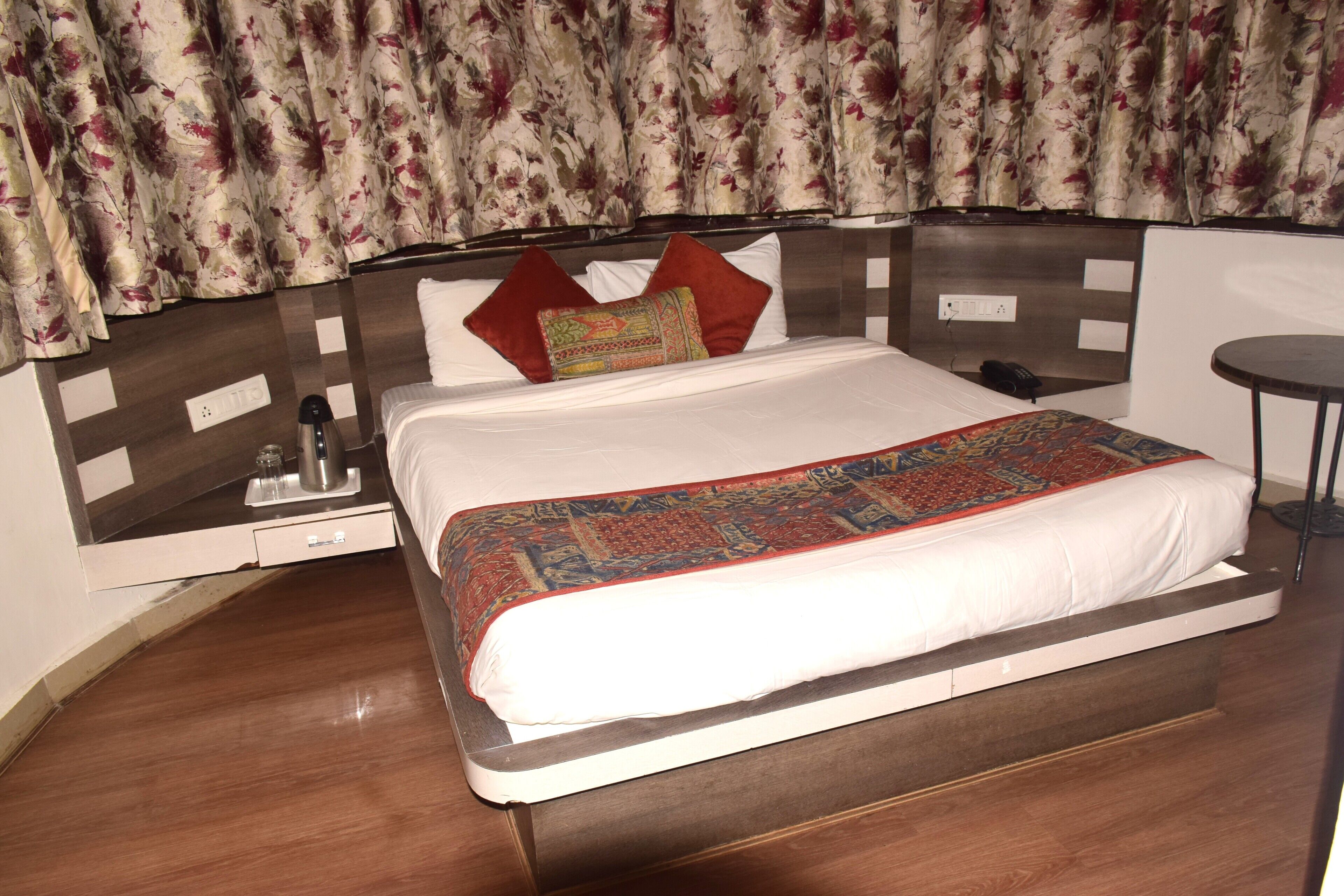 Una habitación de hotel con una cama, una mesita de noche, una silla y una pequeña mesa.