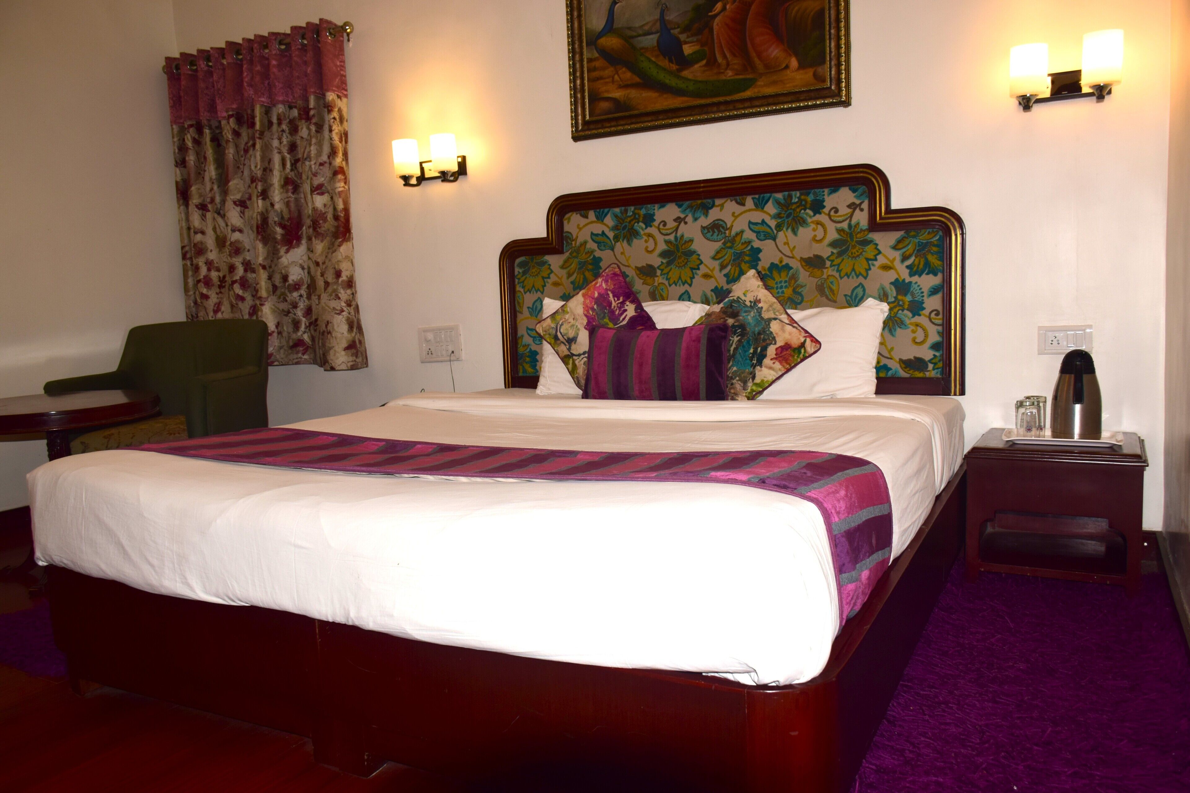 Ein Hotelzimmer mit einem großen Bett, einem Sessel, einem Nachttisch und einem Bild an der Wand.