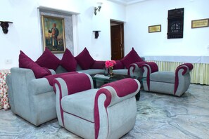 Una habitación con un conjunto de sofás, una mesa de centro, un cuadro y una puerta.
