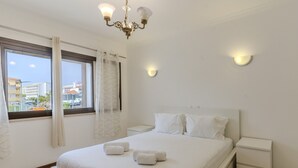 A hotel room with a bed, bedside tables, a chandelier, and a window with curtains. - #367 Cozy Orion Apartment | Pool & Balcony (Albufeira)