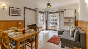 A dining area with a wooden table, chairs, and a breakfast spread. - #367 Cozy Orion Apartment | Pool & Balcony (Albufeira)
