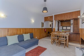 Ett modernt vardagsrum med en soffa, ett matbord och ett kök i bakgrunden.