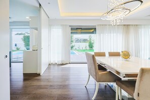 Ein stilvolles Esszimmer mit einem weißen Tisch, beigen Stühlen und einer Chandelier.