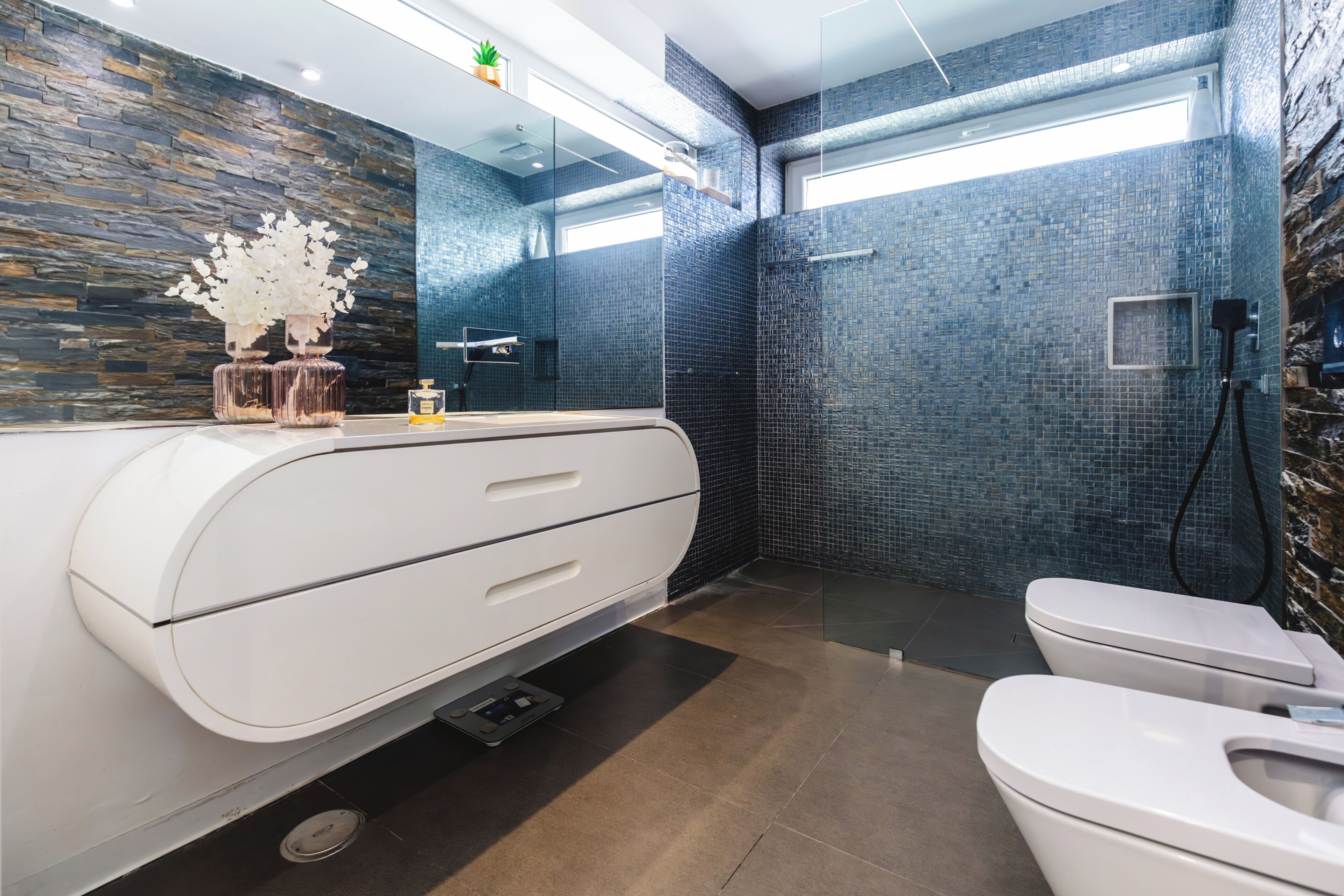 Un bagno moderno con un mobile lavabo bianco, cabina doccia in vetro e rivestimento in piastrelle.
