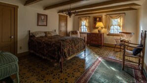 Een klassieke kamer met een bed, een dressoir, een stoel en een kroonluchter.
