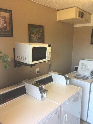 A laundry area with a microwave, washing machine, and dryer. - Days Inn by Wyndham Victorville/hesperia I-15 & P (Victorville)