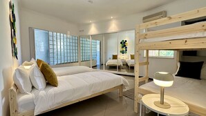 A modern bedroom with a bunk bed, a bedside table with a lamp, a large window with a view, and a decorative wall piece. - Yellow | Private pool | 12 Pax | Albufeira (Albufeira)