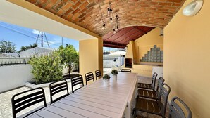 An outdoor patio with a brick ceiling, a long table with chairs, and a tiled backsplash. - Yellow | Private pool | 12 Pax | Albufeira (Albufeira)