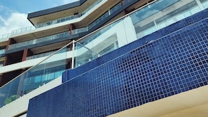 Ein mehrstöckiges Gebäude mit moderner Architektur, mit Glasbalkonen und einer blau gefliesten Fassade.