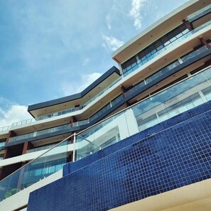 Ein mehrstöckiges Gebäude mit moderner Architektur, mit Glasbalkonen und einer blau gefliesten Fassade.