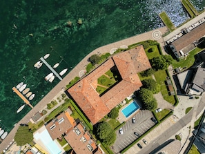 Luftaufnahme eines Küsteneigentums mit Schwimmbad, anliegenden Bootstständen und einer Mischung aus Wohn- und Geschäftsgebäuden.