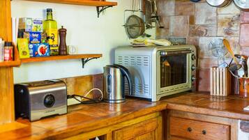 A kitchen with a microwave, toaster, and various kitchen utensils on the counter.