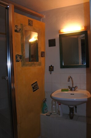 A bathroom with a sink, mirror, and a door with a small picture frame.