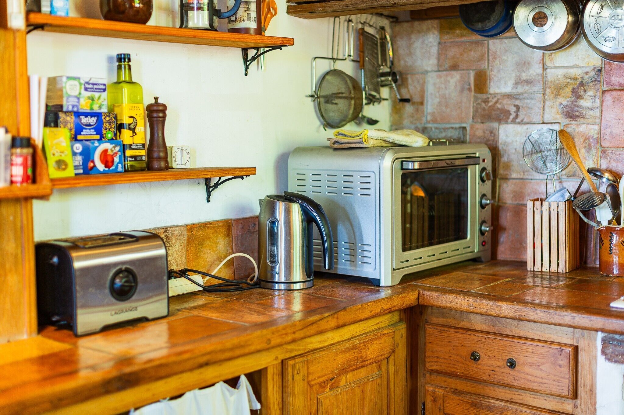 A kitchen with a microwave, toaster, and various kitchen utensils on the counter.