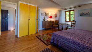 Une chambre à coucher comprenant un lit, une commode, une chaise, une table et une fenêtre donnant sur un beau paysage.