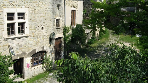 Ein Steinhaus mit mehreren Fenstern und einem schmalen Weg zum Eingang.