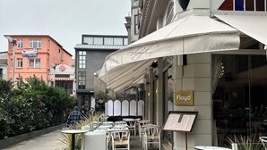 An outdoor seating area with tables and chairs, a menu board, and a sign for 'Floyd Lounge Bar'. - Port Hotel (Istanbul)