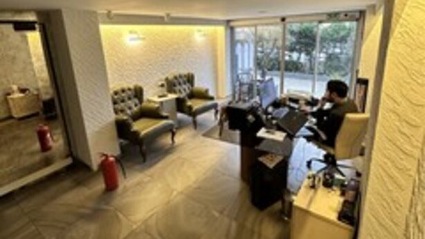 A modern office space with a desk, computer, and a chair. There is a window with a view of the outside. - Port Hotel (Istanbul)