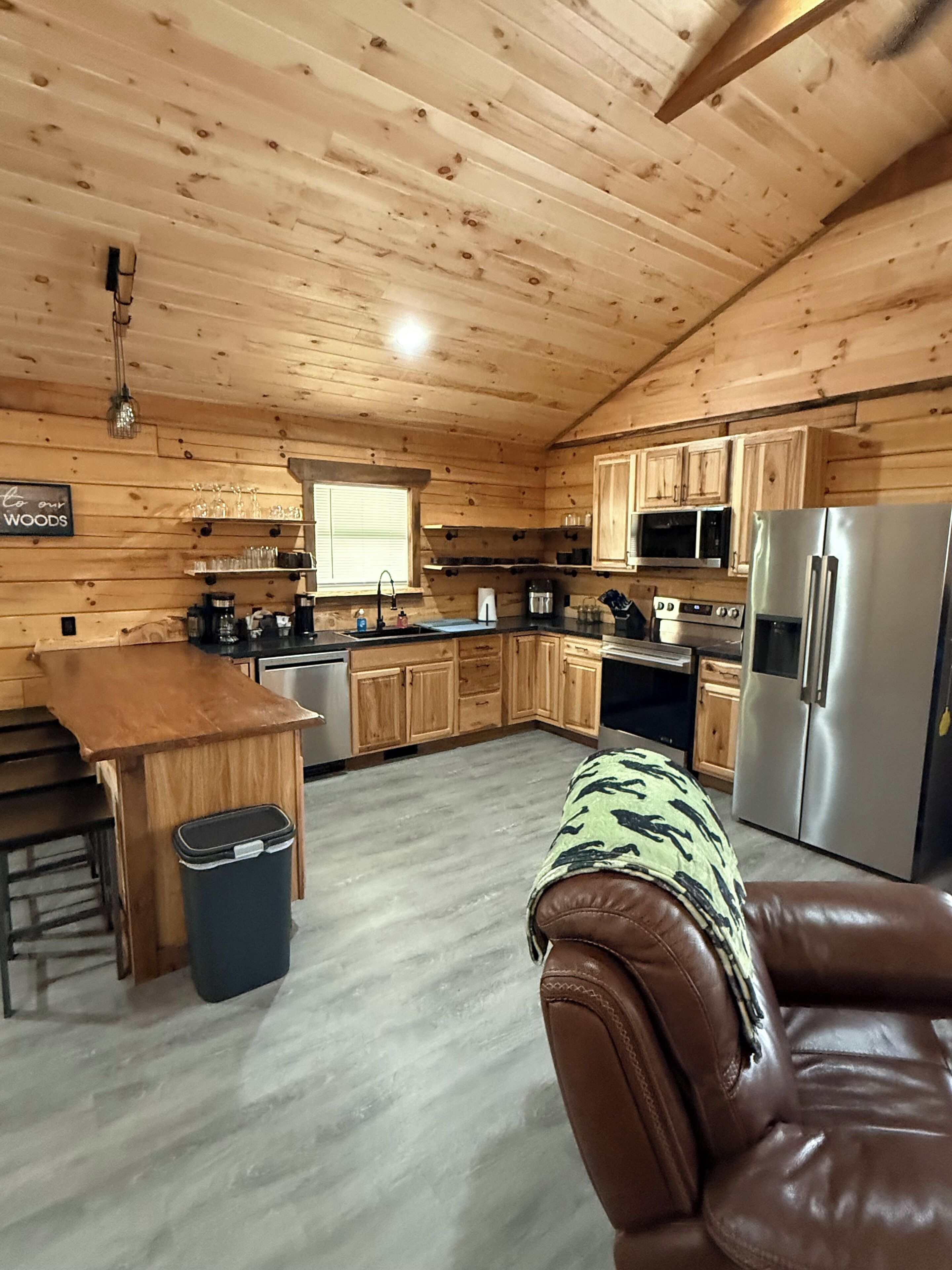 L’intérieur d’un chalet en bois comprend une cuisine, un coin repas et un canapé en cuir.