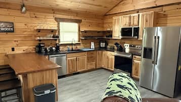 L’intérieur d’un chalet en bois comprend une cuisine, un coin repas et un canapé en cuir.