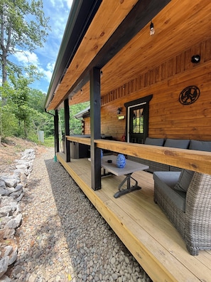 A wooden deck with outdoor seating, a stone pathway, and a view of the surrounding forest.