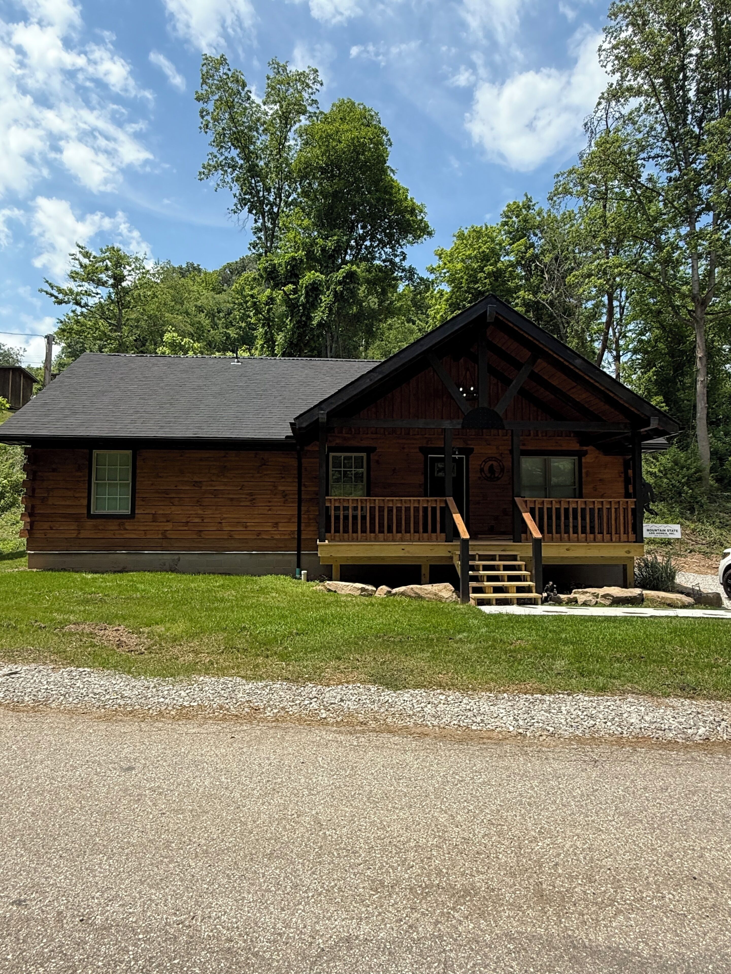 Une cabane en bois dotée d’un porche, d’une petite entrée et d’un panneau indiquant qu’il s’agit d’un terrain de camping situé en montagne.