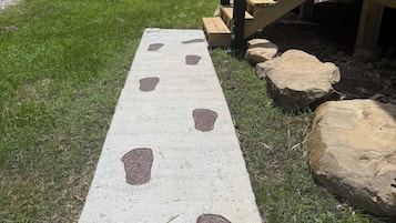A concrete path with footprints leading to a wooden deck with a staircase.