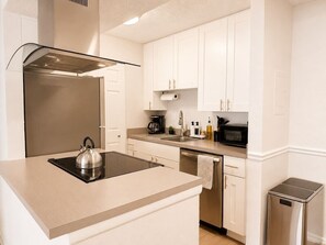 A modern kitchen with a built-in stove, stainless steel appliances, and white cabinetry. - Stylish Tampa Getaway | Airport, Stadiums & Beaches (Tampa)