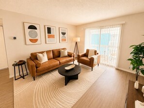 A living room with a brown leather sofa, a black coffee table, a side table, and a potted plant. - South Tampa Retreat | Near Airport & Downtown (Tampa)