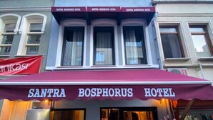 A hotel entrance with a marquee sign, large windows, and potted plants. - Santra Bosphorus Pansiyon (Istanbul)