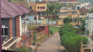 Un quartiere residenziale con case, una strada stretta e uno sfondo collinare.