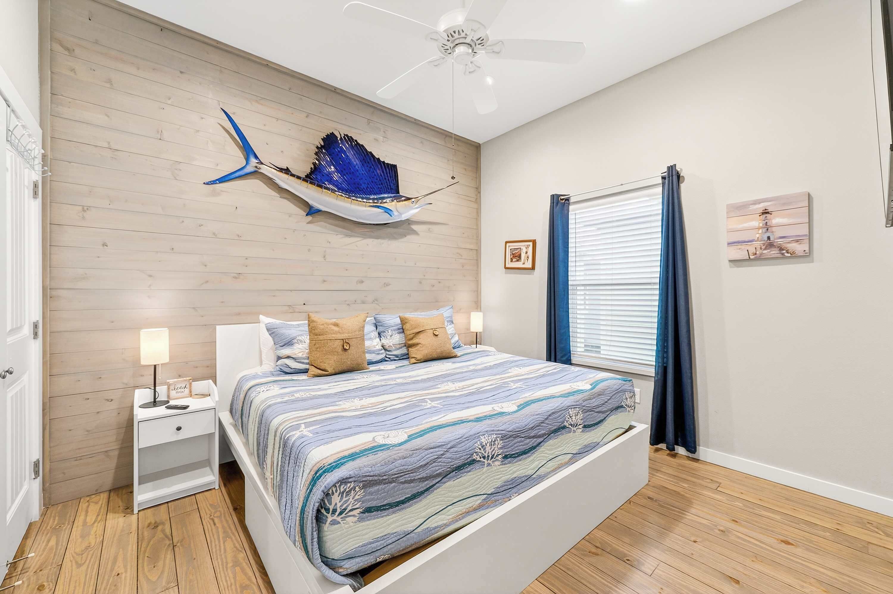 A bedroom with a bed, nightstands, a ceiling fan, a wooden wall, and a decorative fish.