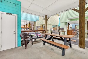 Uma área de estar coberta ao ar livre com bancos e uma mesa, rodeada por edifícios coloridos.
