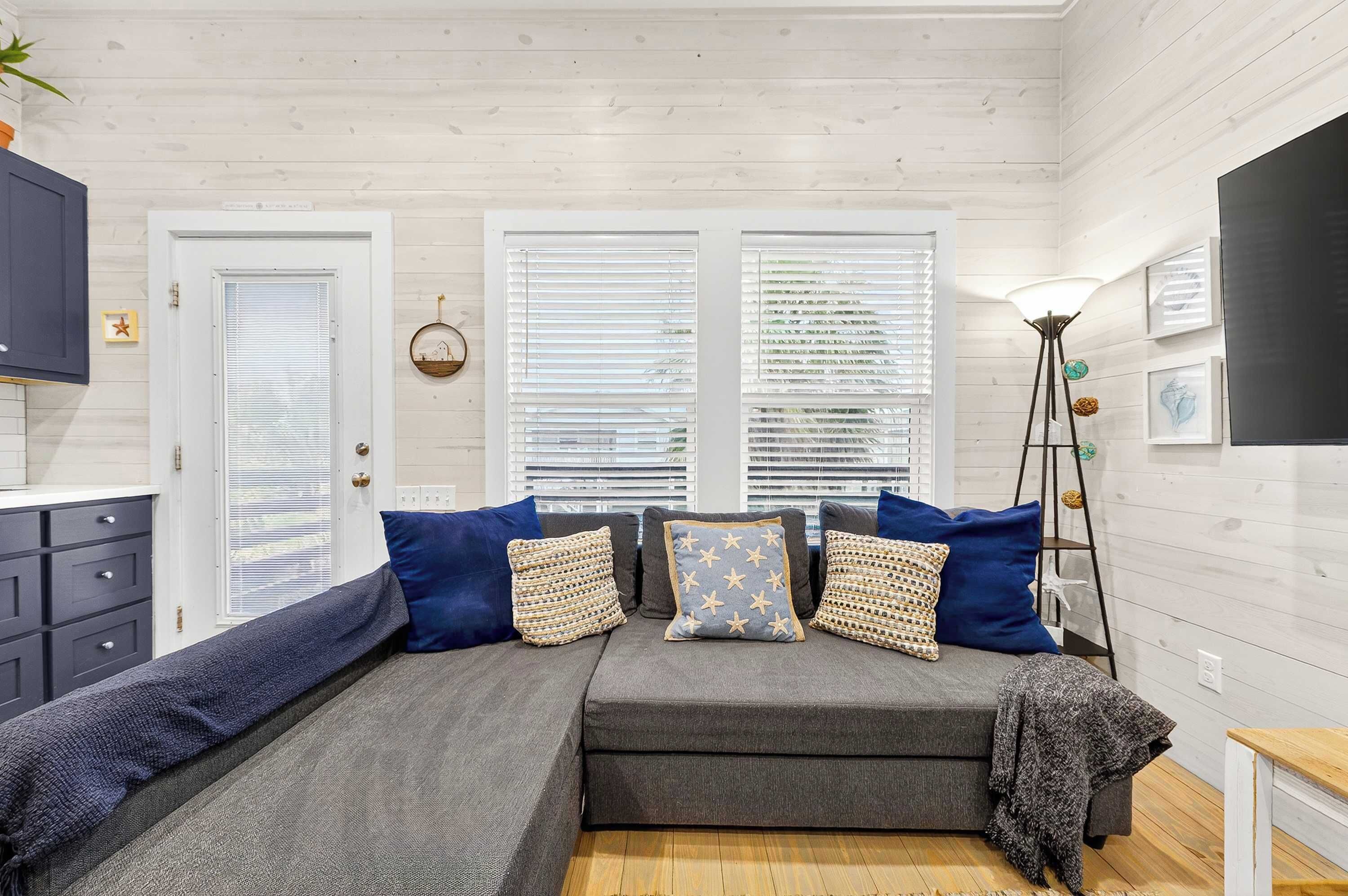A cozy room with a sofa set, a floor lamp, and a view through the windows.