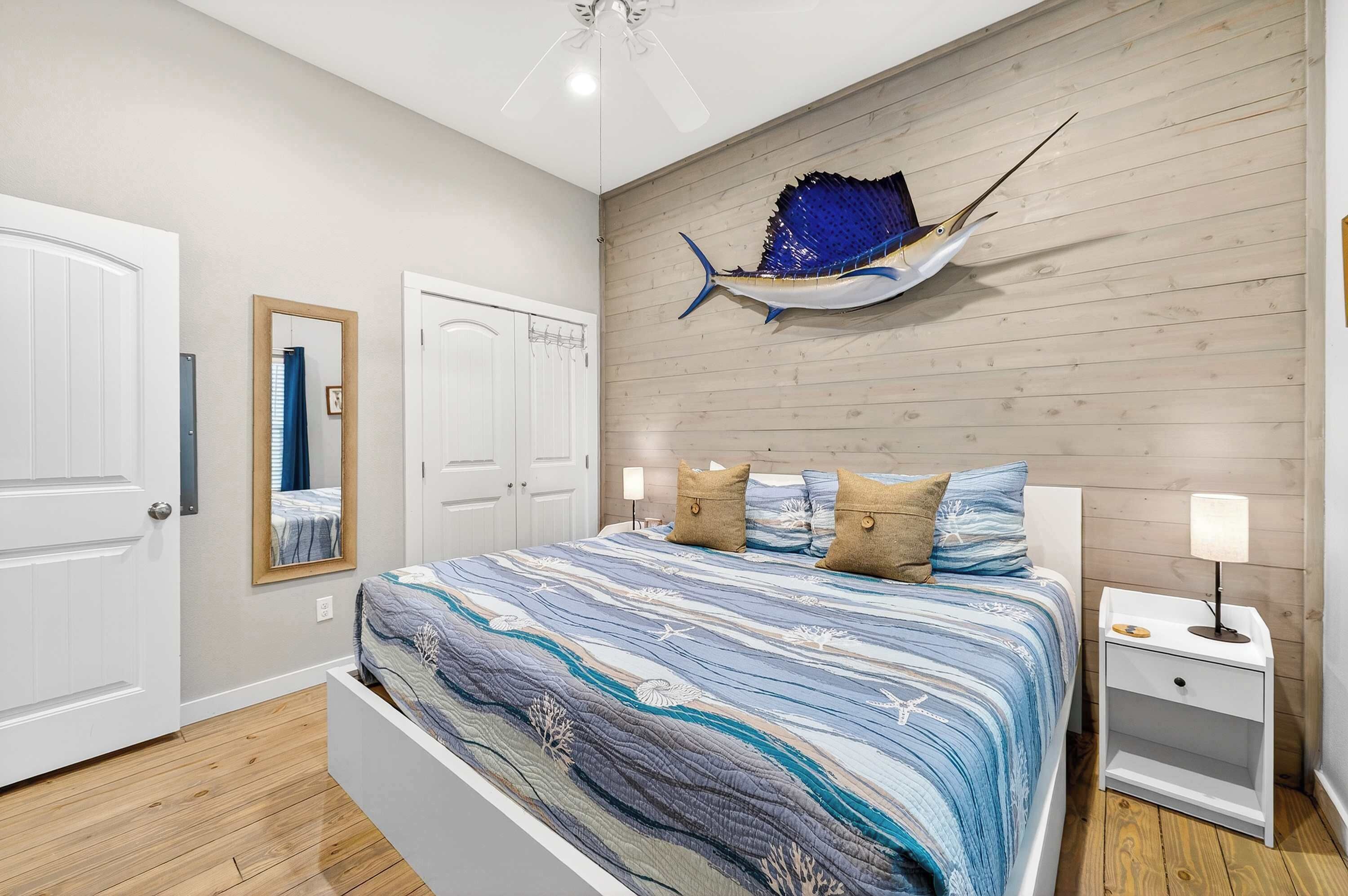 A bedroom with a bed, a nightstand, a wall-mounted fish decoration, and a ceiling fan.