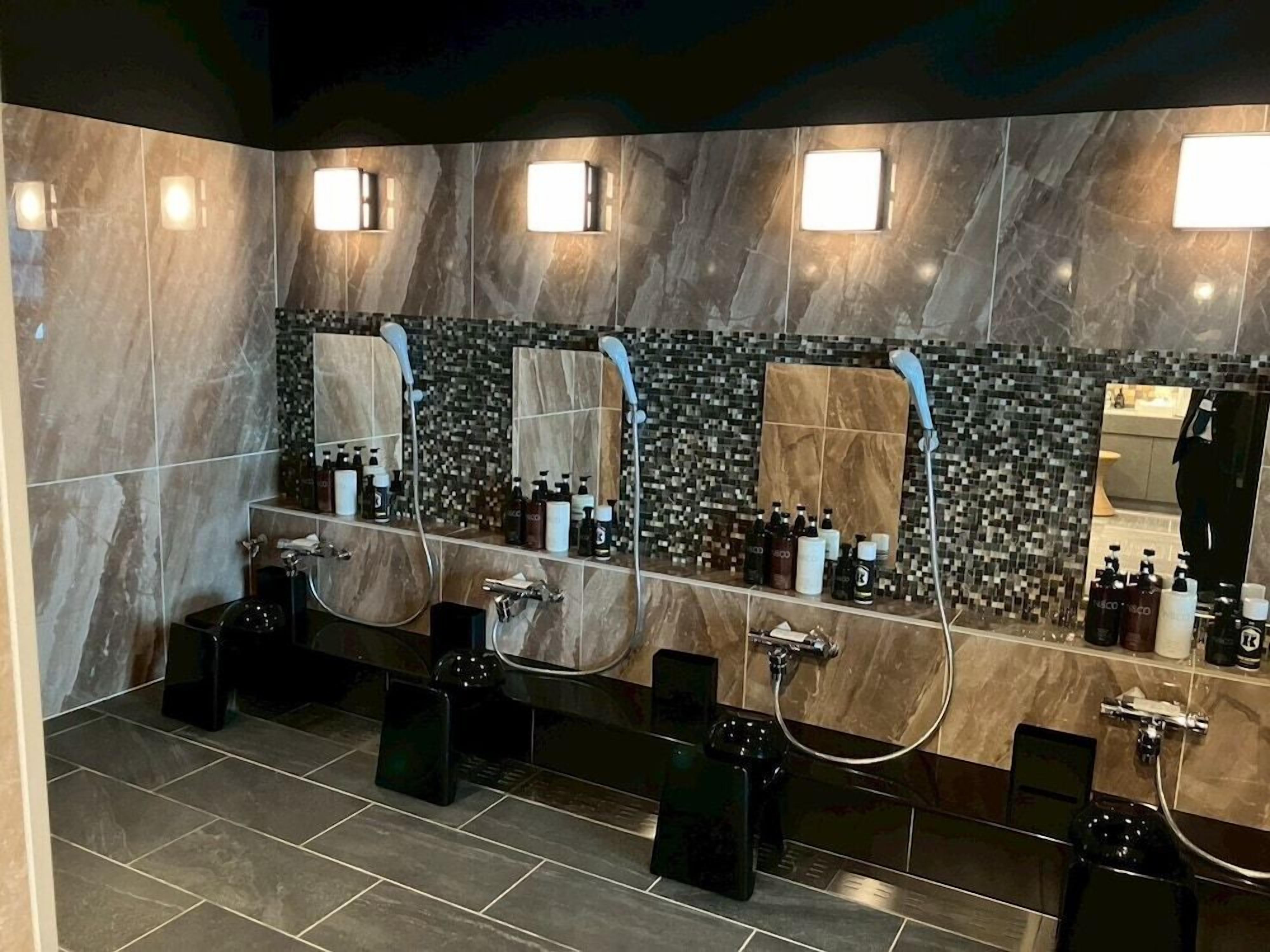 A modern bathroom with marble walls, multiple sinks, and mirrors.