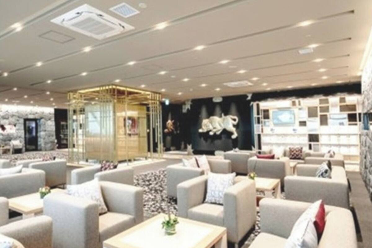 A modern lounge area with sofas and tables, a decorative wall with a lion sculpture, and a patterned wall in the background.