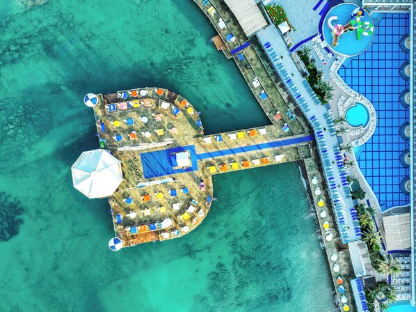 An aerial view of a resort with a pool, multiple sun loungers, and a central structure with a large umbrella. - Orange County Alanya Family Concept (ANTALYA)
