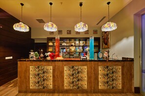 Uma área de bar com painéis de madeira, luminárias de vidro colorido penduradas e diversos objetos decorativos no balcão.