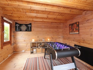 Ein Holzraum mit einem Tischkicker, Dartscheiben und einem gerahmten Kunstwerk.