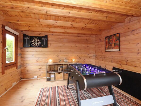 Ein Holzraum mit einem Tischkicker, Dartscheiben und einem gerahmten Kunstwerk.