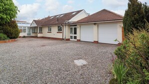 A two-story house with a gravel driveway, a garage, and a conservatory. - Meadowcroft (Watchet)