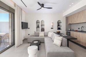Ein modernes Wohnzimmer mit einem grauen Ecksofa, einem schwarzen Couchtisch und einem Deckenventilator.